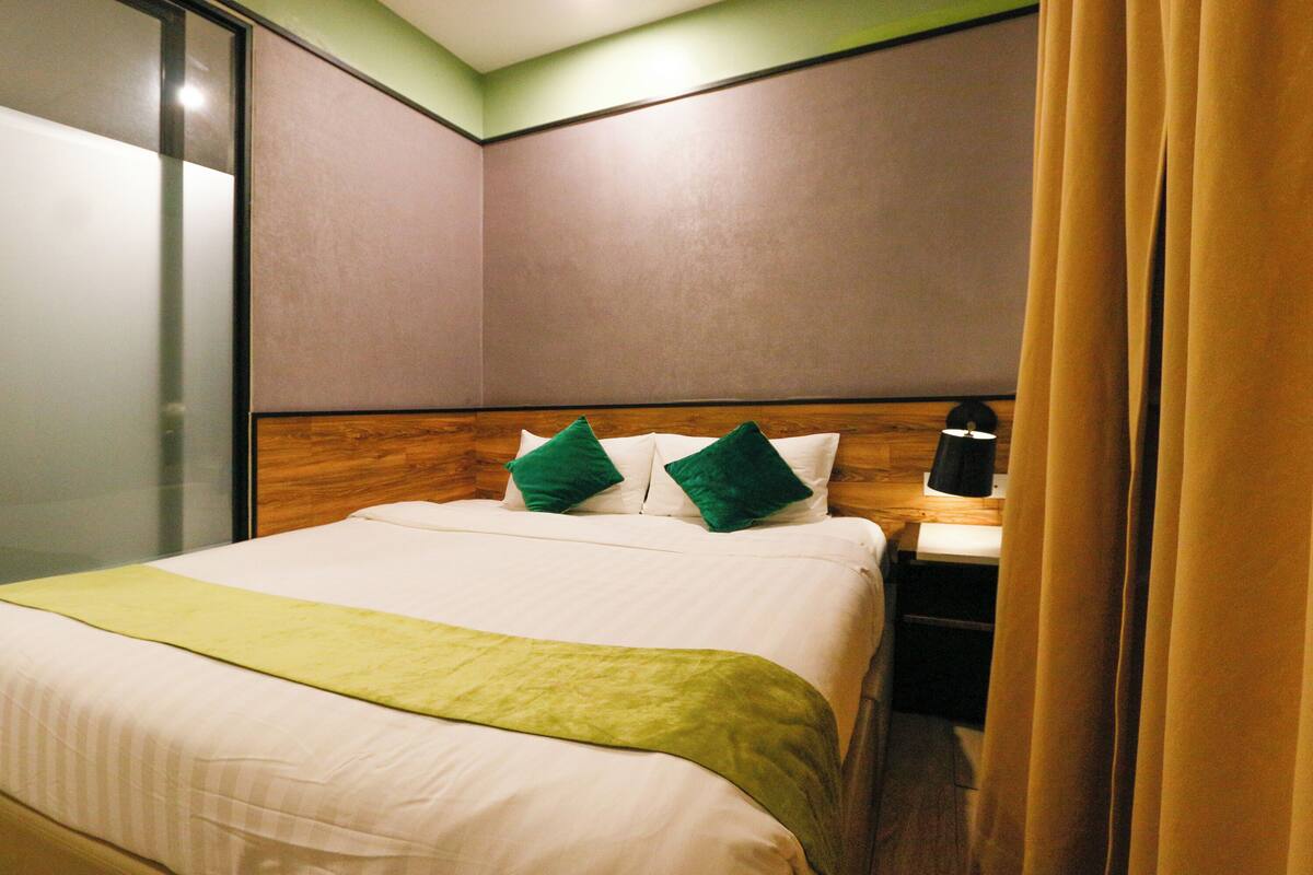 A hotel room with a bed, a bedside table, and a nightstand.