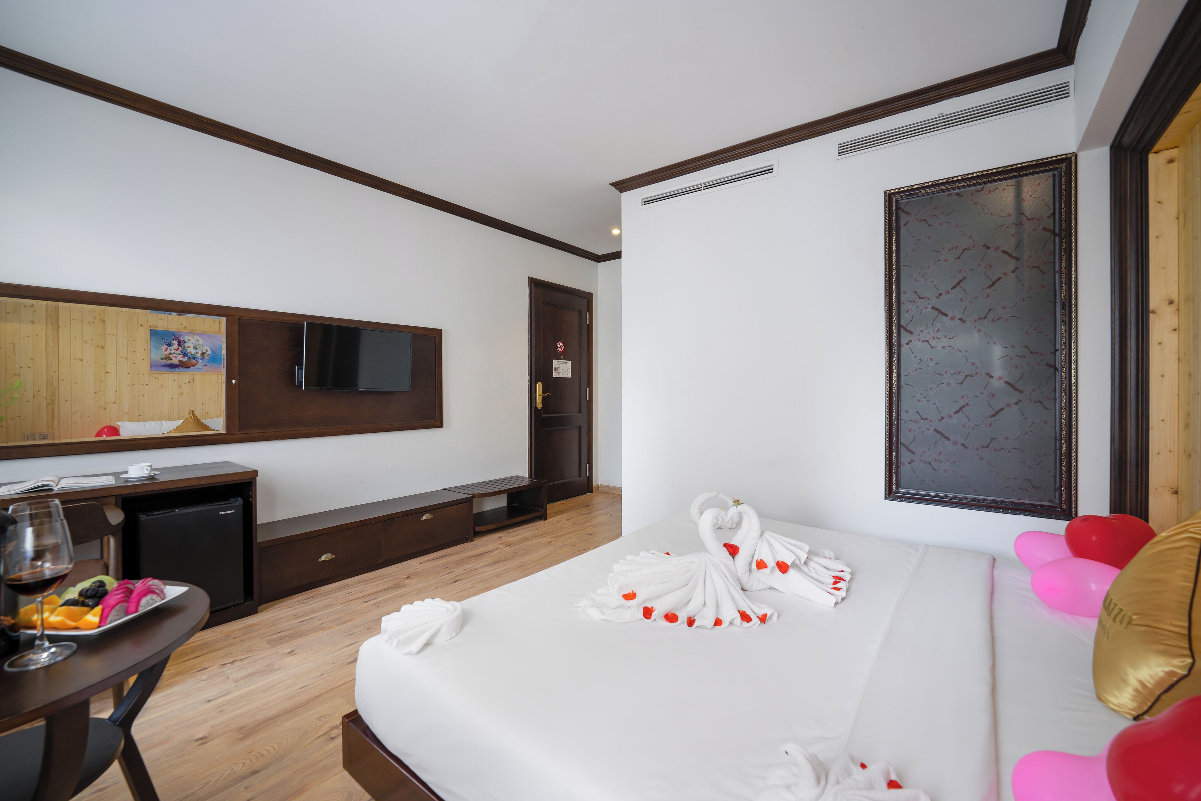 A hotel room with a bed, a desk with a computer, a television, and a large window.