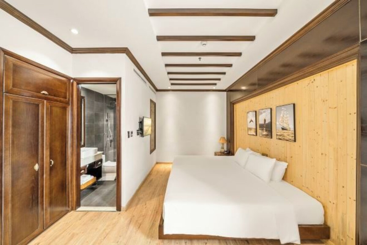 Quarto com cama grande, guarda-roupa de madeira e espelho.
