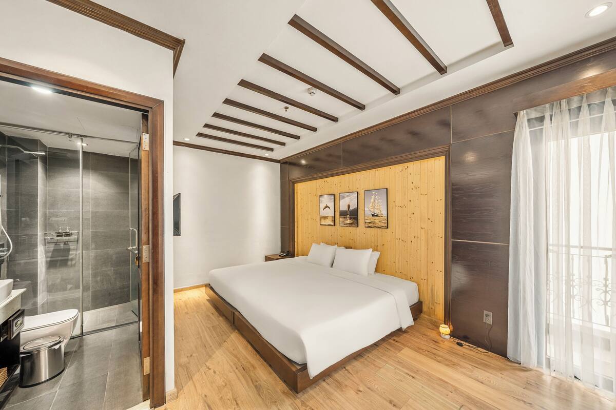 Ein modernes Schlafzimmer mit einem großen Bett, einer Wand aus Holzpaneelen und einer Duschkabine aus Glas.