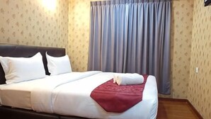 A neatly made bed with white linens and a red throw, a dark headboard, and a window with curtains. - Classic Kinabalu Hotel (Kota Kinabalu)