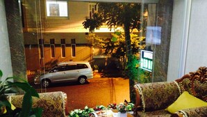 Een kamer met uitzicht op een straat, een geparkeerde auto en een tafel met een tijdschrift.