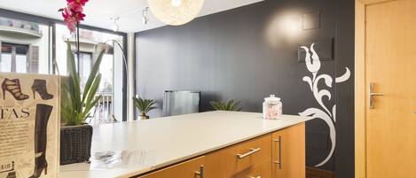 A modern kitchen with a white countertop, wooden cabinets, and a hanging light fixture.