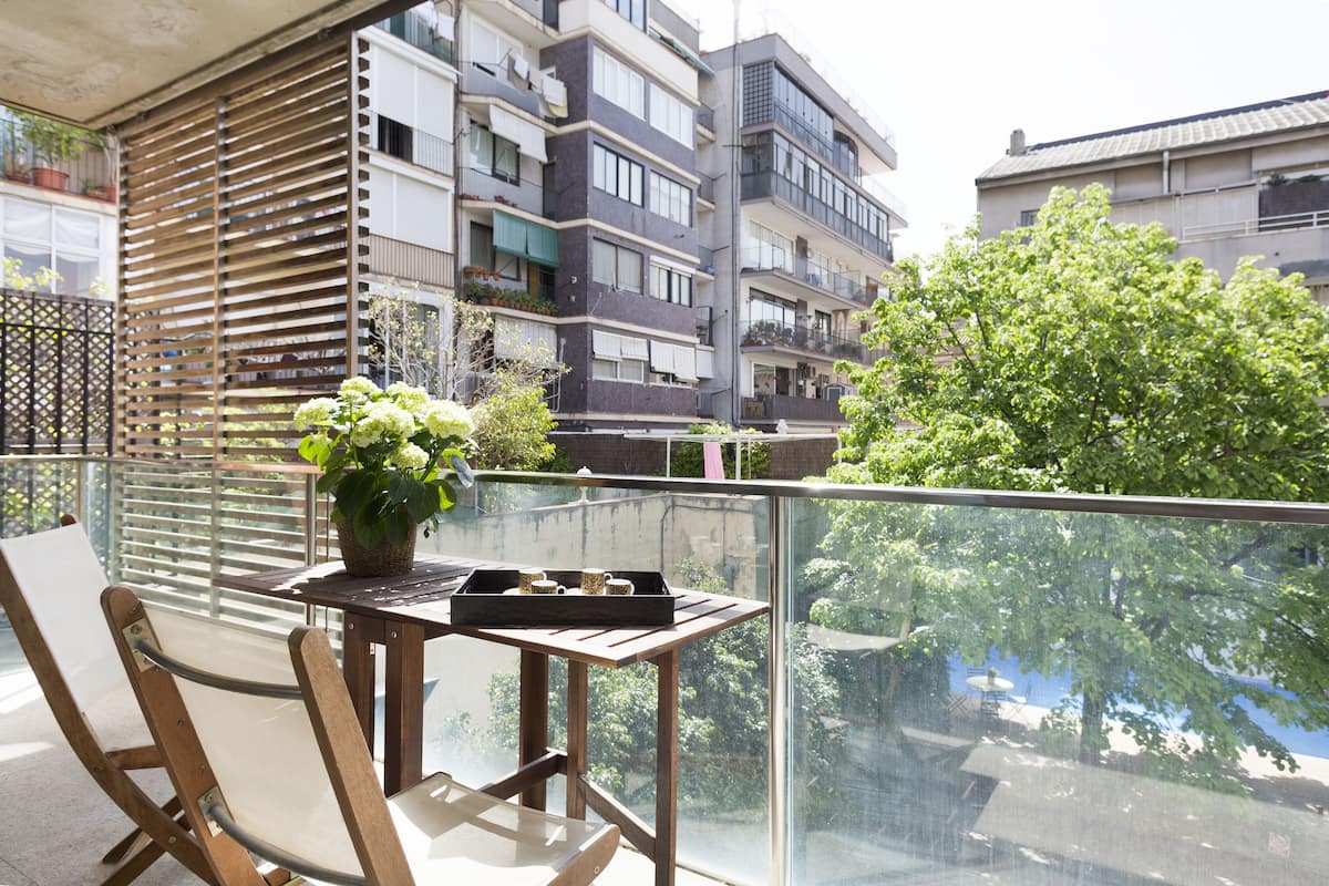 Un balcón con una mesa de madera, una silla y una planta en maceta.