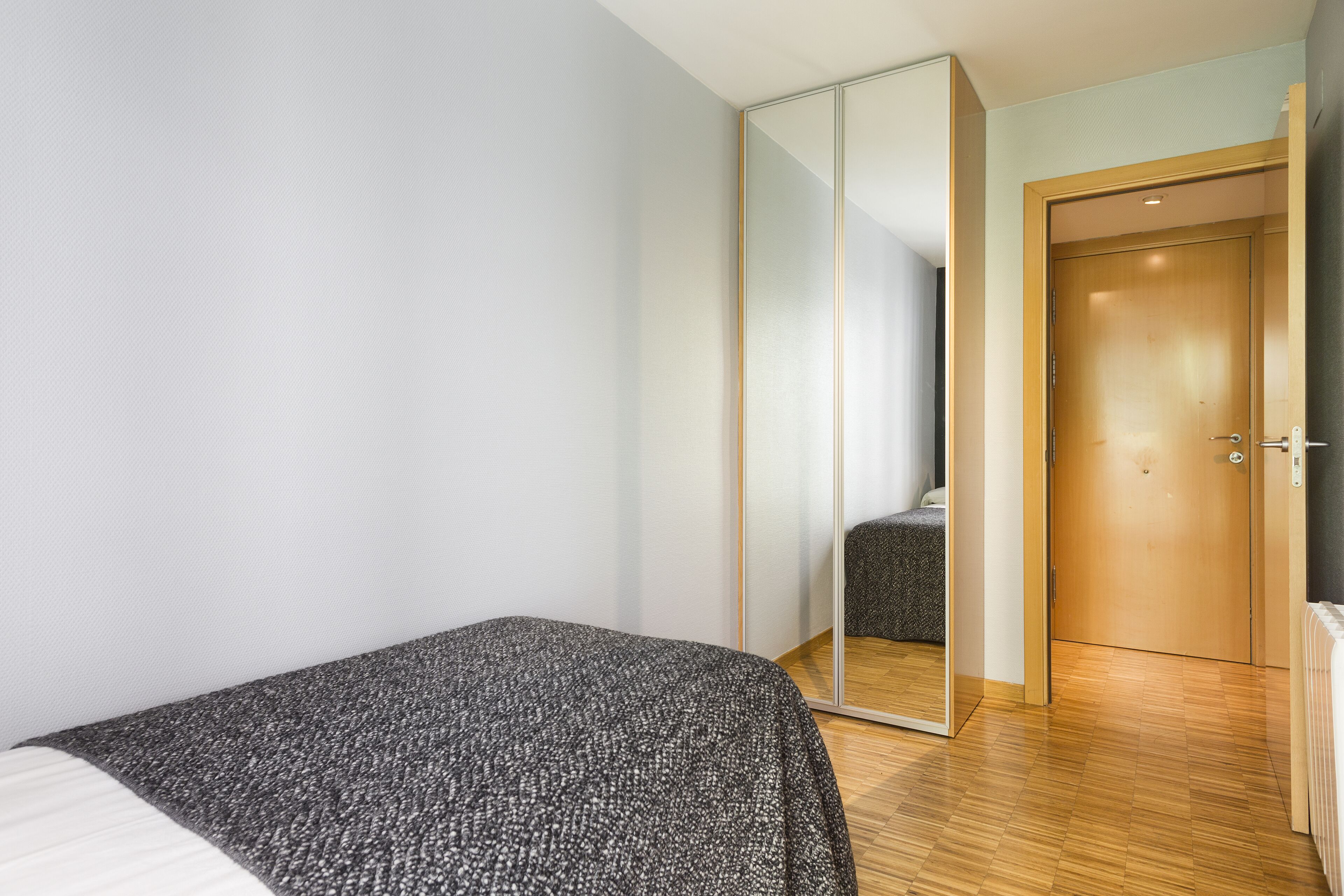 A bedroom with a bed, a wardrobe, and a door.