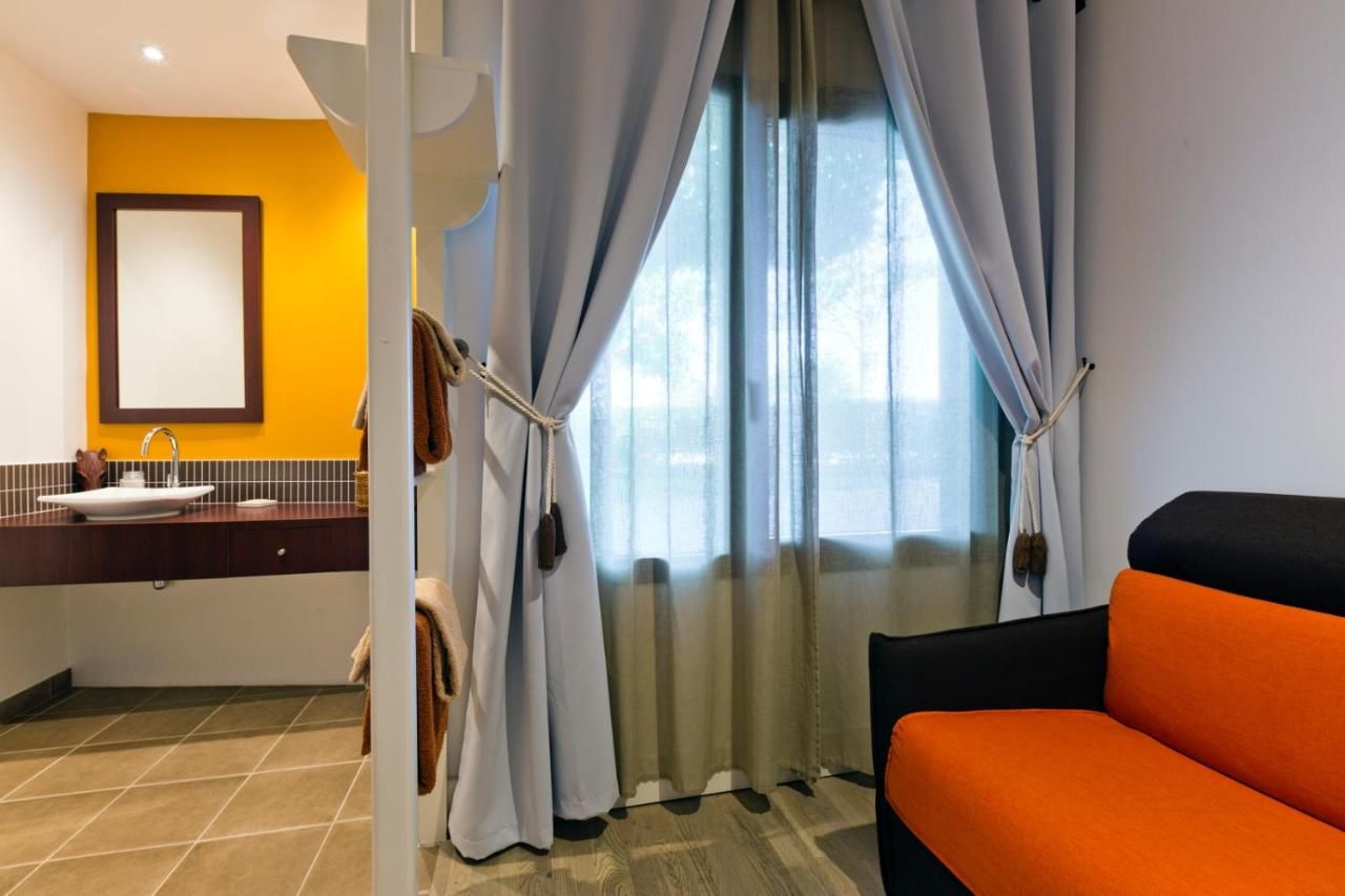 A hotel room with a bed, a bathroom with a sink, and a window with curtains.