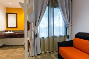 Une chambre d’hôtel avec un lit, une salle de bain avec un lavabo et une fenêtre avec des rideaux.