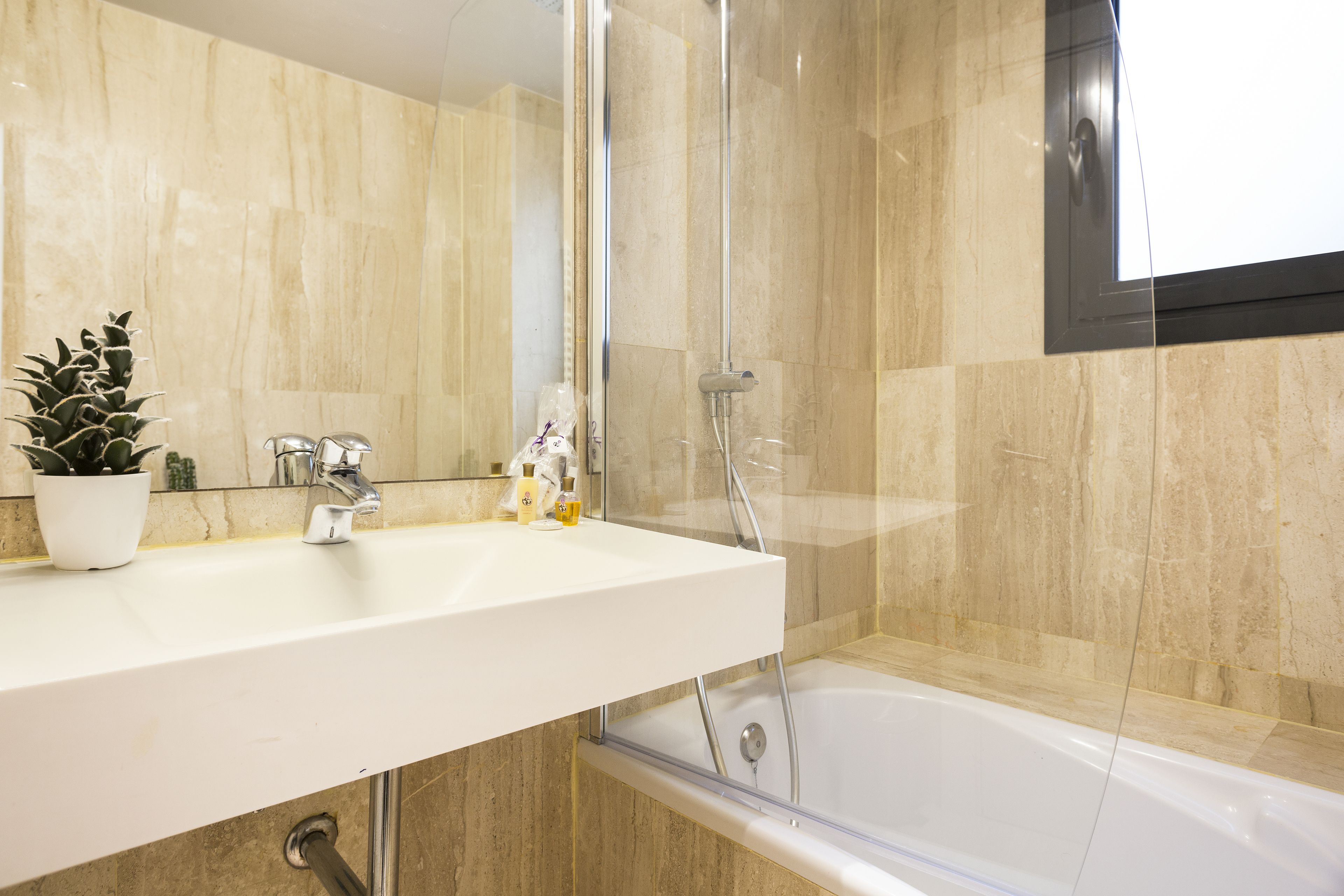 Un baño con lavamanos blanco, cabina de ducha de cristal y bañera.