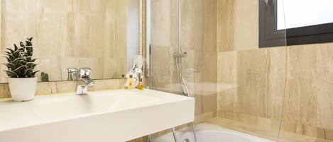 Un baño con lavamanos blanco, cabina de ducha de cristal y bañera.