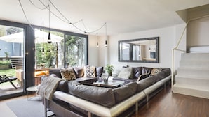 Ein modernes Wohnzimmer mit einem großen Ledersofa, einem Couchtisch und einer Treppe.