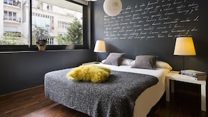 Ein modernes Schlafzimmer mit großem Fenster, einem Bett mit flauschigem gelben Kissen, zwei Nachttischlampen und einer Wand mit handgeschriebenem Text.