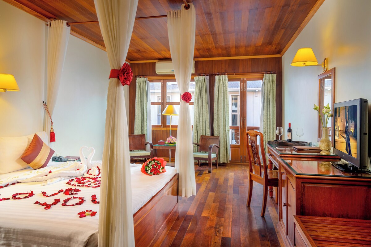 A hotel room with a bed, a desk, a TV, and a view of the outside.