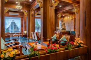 A wooden interior with a dining area, chairs, and a statue.