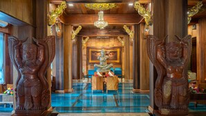 Un intérieur traditionnel en bois, avec une statue centrale, un sol recouvert de carreaux bleus et des décorations dorées élaborées.