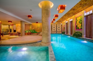 A hotel lobby with a pool, a reception area, and a dining space.