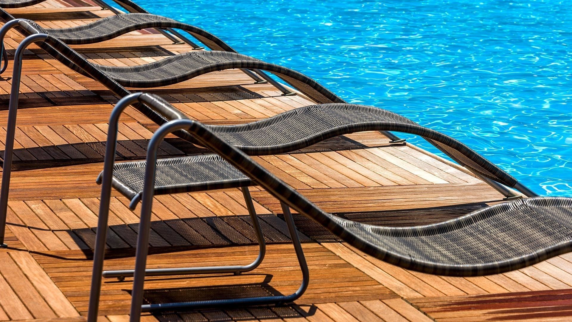 A poolside area with multiple lounge chairs and a wooden deck.