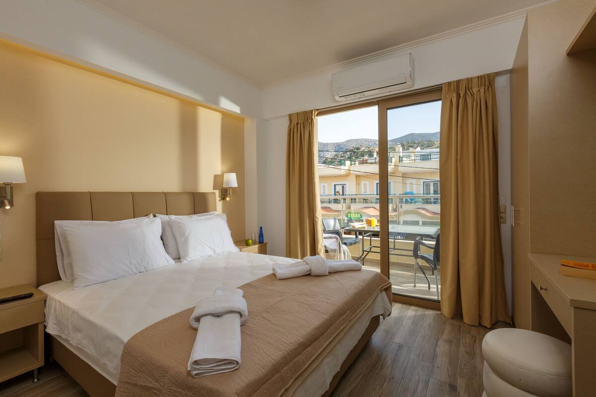 Habitación de hotel con una cama grande, un escritorio y vista a la ciudad.