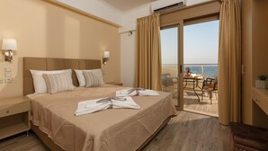 A hotel room with a large bed, two bedside lamps, a view of the sea, and a balcony with outdoor seating. - Panorama Hotel Apartments (Hersonissos)