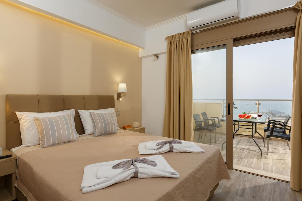Habitación de hotel con cama, mesita de noche y vistas al balcón.