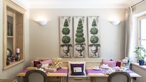 A dining area with wooden tables, cushioned benches, and a wall-mounted light fixture. - Pension Waldruhe (Grundlsee)