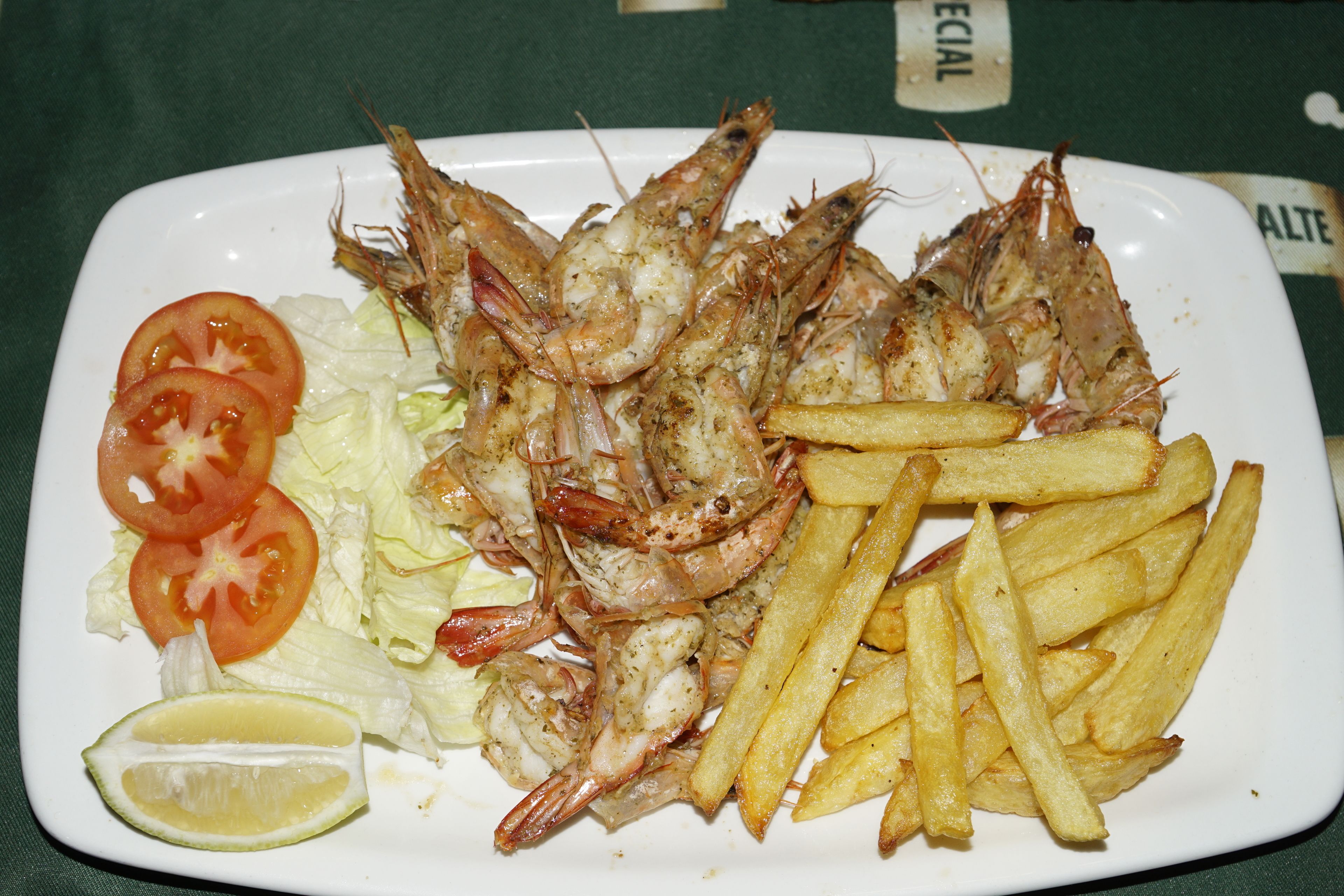 A plate of grilled shrimp with fries and vegetables.
