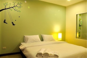 Ein Hotelzimmer mit einem Bett, Kissen und aufgerollten Handtüchern auf dem Bett.