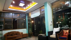 Eine moderne Hotelhalle mit einer Couch, Sesseln und einer Glastrennwand.