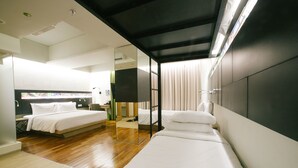 Een moderne hotelkamer met een groot bed, een kleiner bed, een bureau en een spiegel.