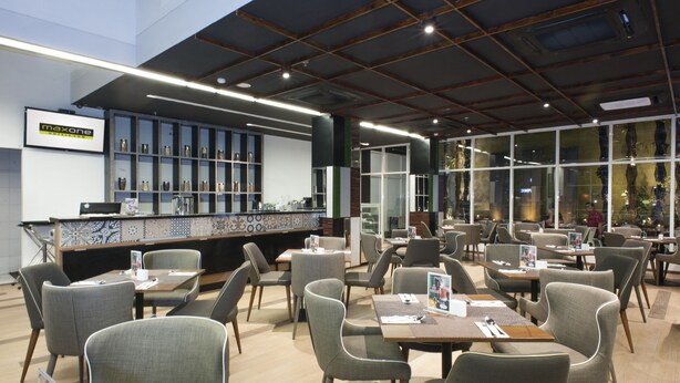 Een modern restaurant met een bar, diverse zitplaatsen en grote ramen.