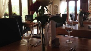 Zona pranzo con tavolo apparecchiato per due, un vaso con fiori, bicchieri da vino e un espositore per i menu.