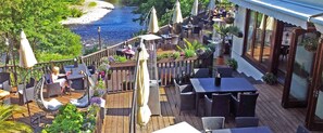 An outdoor deck with wooden flooring, outdoor seating, and a river view. - White Waters Country Hotel (Llangollen)