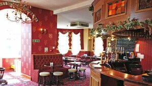 Un ristorante con pareti rosse, tappeto decorato e arredi in legno.