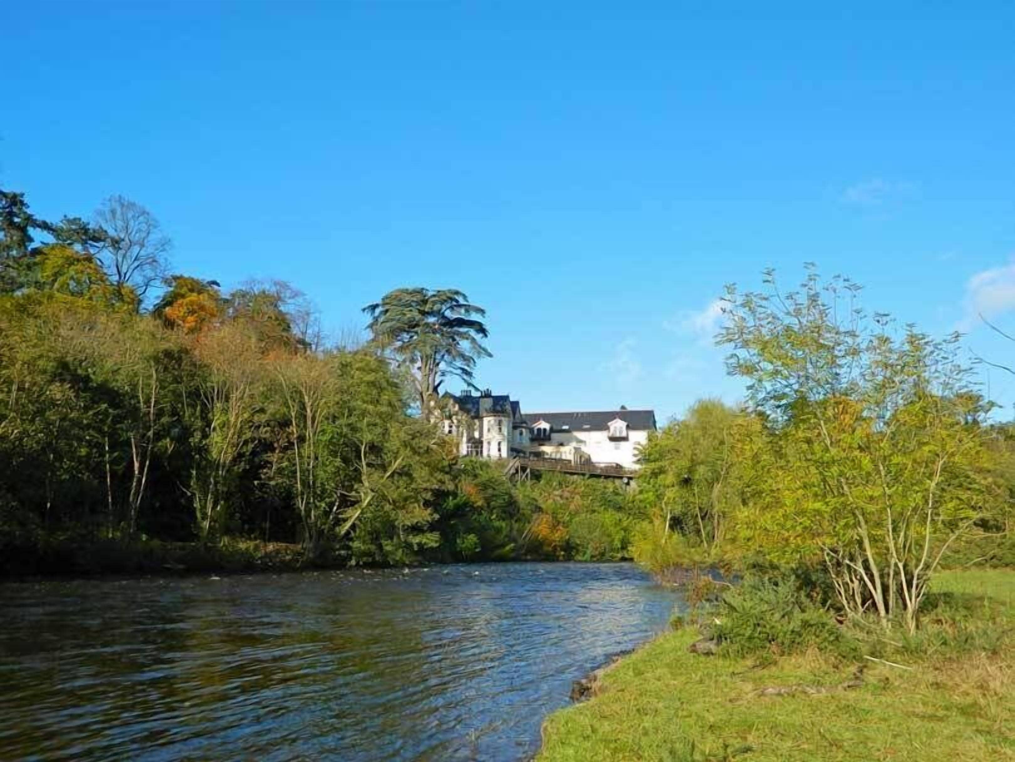 Une rivière avec une maison en arrière-plan.
