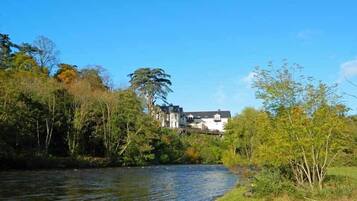 Une rivière avec une maison en arrière-plan.