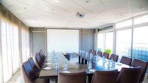 A conference room with a long table, chairs, and a projector screen. - Malak Hotel (Rabat)