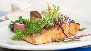 A plate of salmon with vegetables and a mushroom.