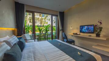 Een moderne hotelkamer met een groot bed, een televisie en een balkon met planten.