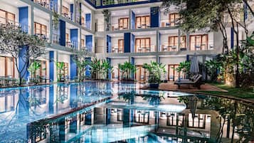 Una piscina al aire libre, sombrillas, sillones reclinables de piscina