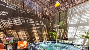 A spa area with a hot tub, seating, and decorative flowers. - Sakmut Boutique Hotel (Siem Reap)
