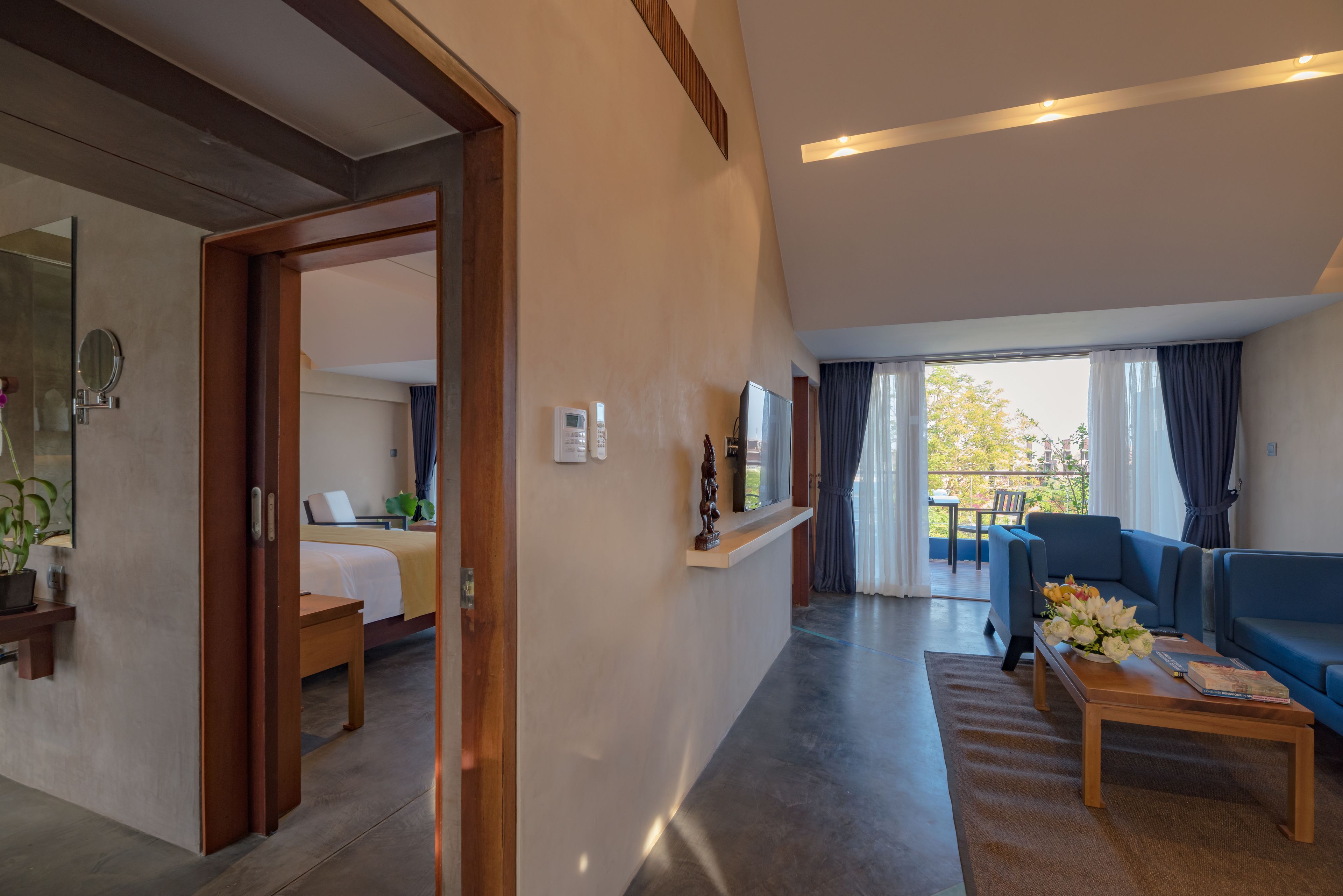 A modern hotel room with a bed, bedside table, and a view of the balcony.