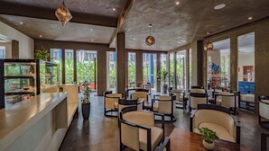 A modern restaurant with a counter, seating area, and large windows. - Sakmut Boutique Hotel (Siem Reap)