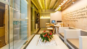 Un moderno vestíbulo de hotel con un mostrador de recepción, zona de estar y un centro de mesa decorativo con plantas.