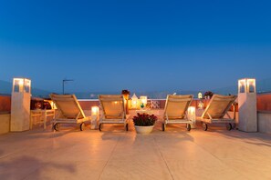 A rooftop terrace with four lounge chairs, a small table, and a potted plant. - Sette Venti Boutique Hotel (Chania)