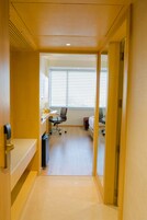 Un pasillo que conduce a una habitación con escritorio, silla de oficina y cama.
