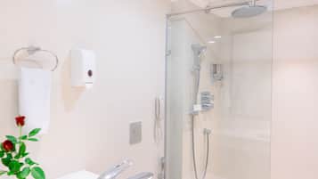 A modern bathroom with a glass-enclosed shower, a white sink, and a soap dispenser.