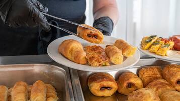Un bufé con diversos pasteles y una persona sirviendo comida.