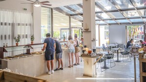 Un restaurante con zona de comedor acristalada, un mostrador de buffet y asientos al aire libre.