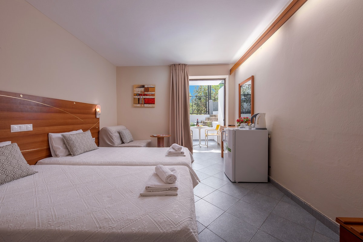 Habitación de hotel con dos camas, un escritorio, un refrigerador y vistas al exterior.