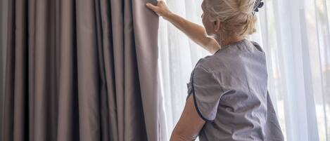 Una persona ajustando las cortinas en una habitación con ventanal.