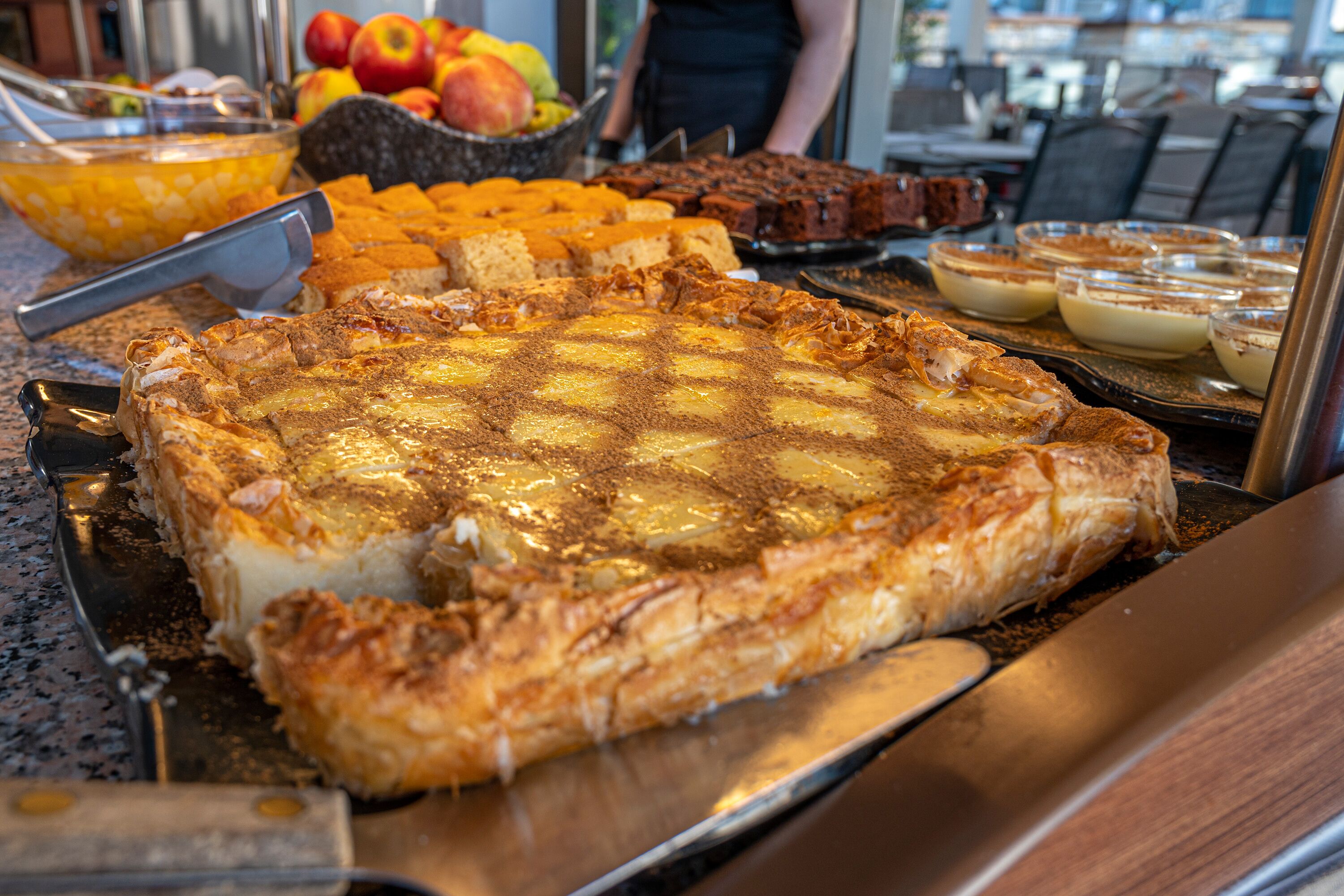 A buffet with various desserts including a large pie, fruit, and other baked goods.